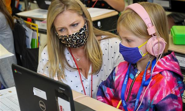 student works with teacher at desk